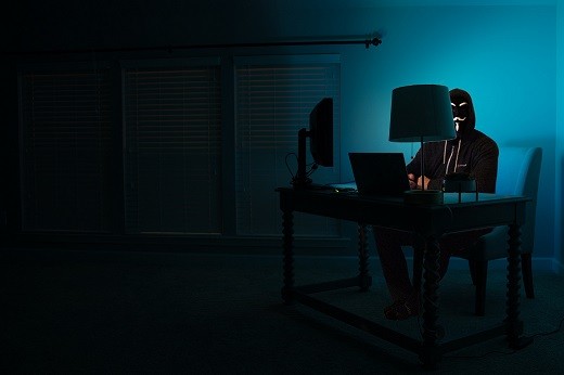 Man sitting facing laptop in dark room