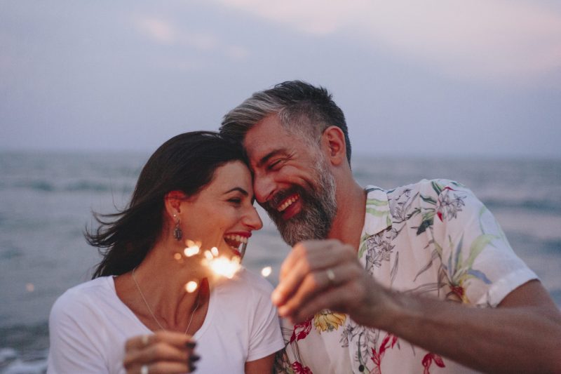 couple celebrating early retirement with sparklers at the beach