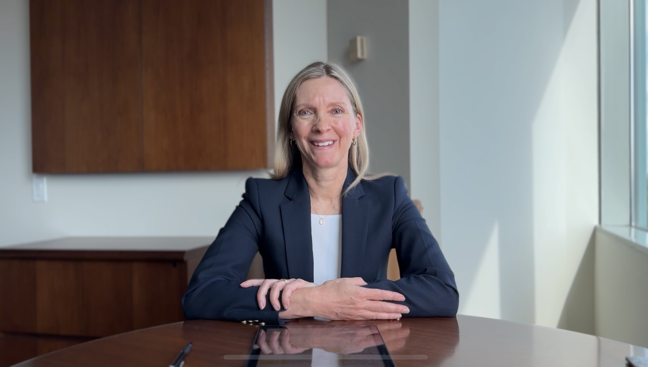 Karen Hubbard, VP, Client Advisory Services, sitting at a desk with arms crossed looking at the camera